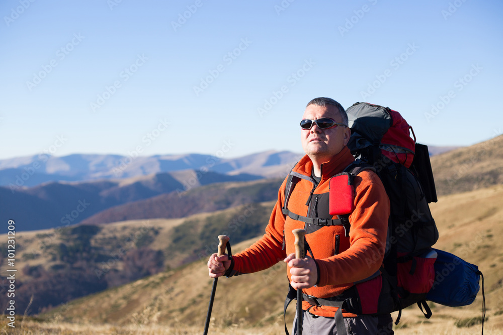 Man hiking in the mountains with a backpack and tent.