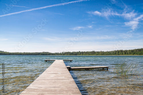Czyste płytkie jezioro i pusty drewniany pomost. Piękna letnia pogoda 