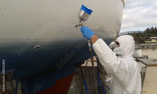 worker spray painting yacht sail boat with spray gun