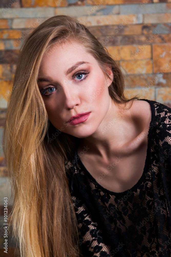 Close up portrait of beautiful young girl in black lace shirt on brick background, serious face expression Close up portrait of beautiful young girl in black lace shirt on brick background, serious face expression