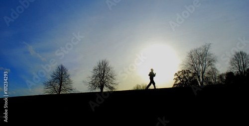 Winter landscape with silhouettes of runners on a horizon at sunset