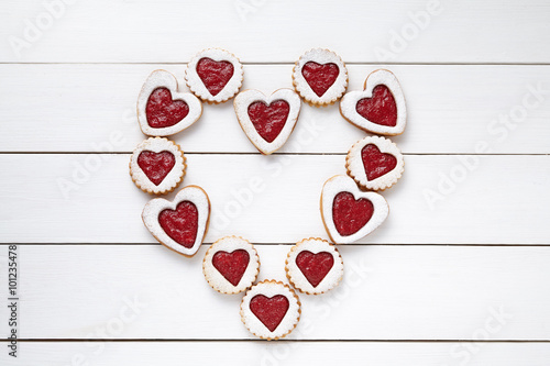 Heart of the shortbread heart-shaped cookies with jam on white wooden table background.