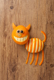 Cat made of orange and grape on wooden background