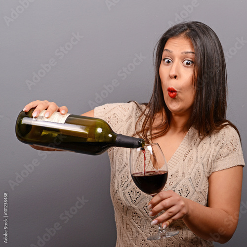 Portrait of woman holding wine bottle and glass against gray bac photo