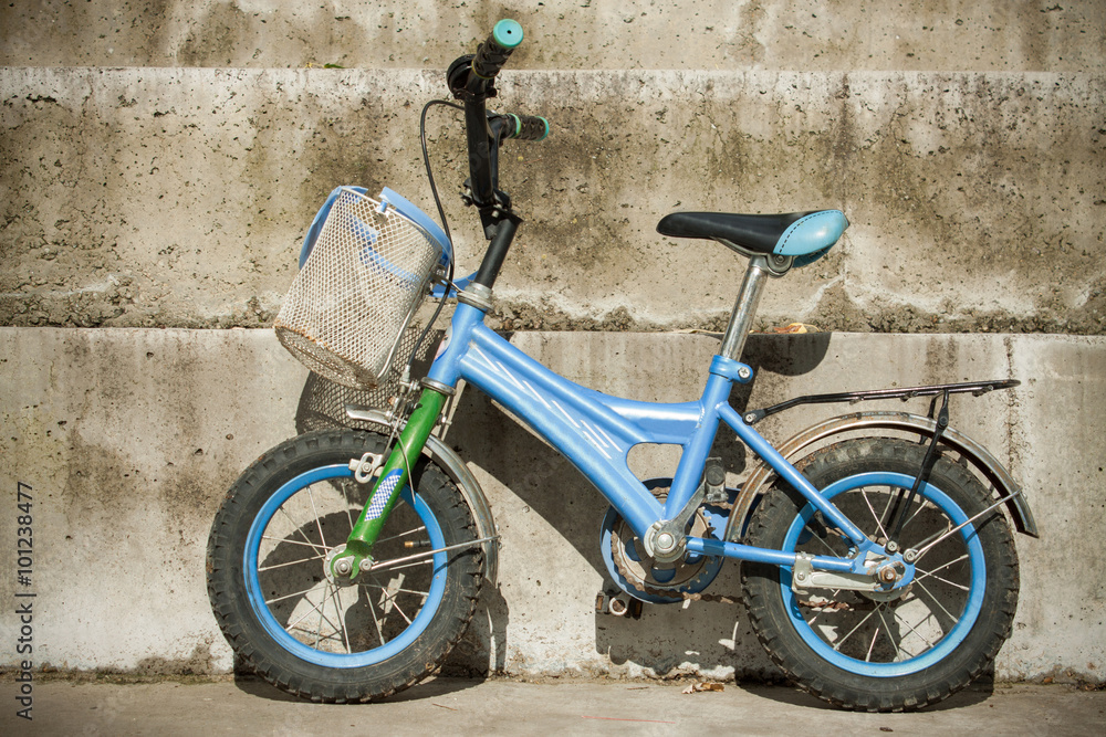 Single blue bicycle on walkway against a stone wall Single blue bicycle on walkway against a stone wall