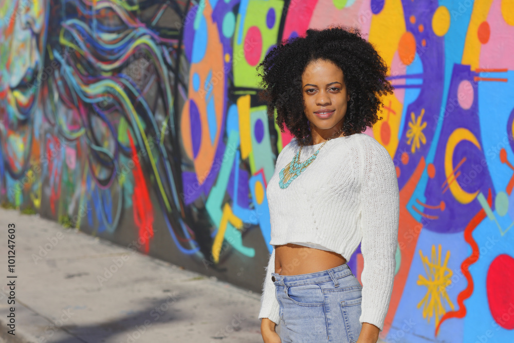 Naklejka premium Woman posing in an urban setting with graffiti