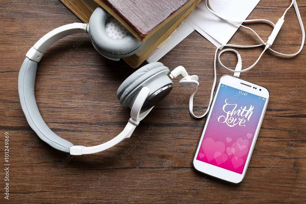 Headphones with old book and smartphone with romantic screensaver Headphones with old book and smartphone with romantic screensaver