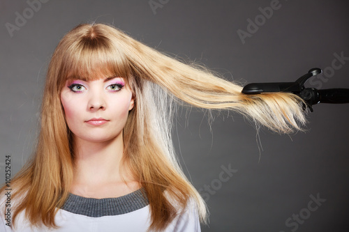 woman making hairstyle with hair iron