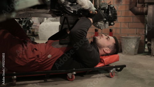Young mechanic in red overalls engaged manual assembly machines