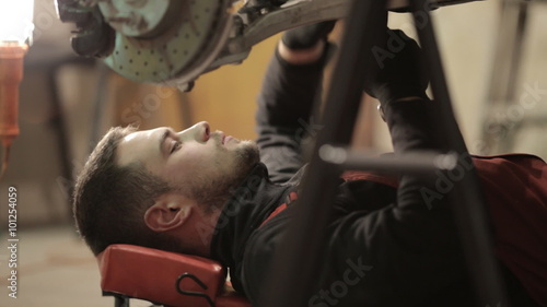 Young mechanic in red overalls engaged manual assembly machines