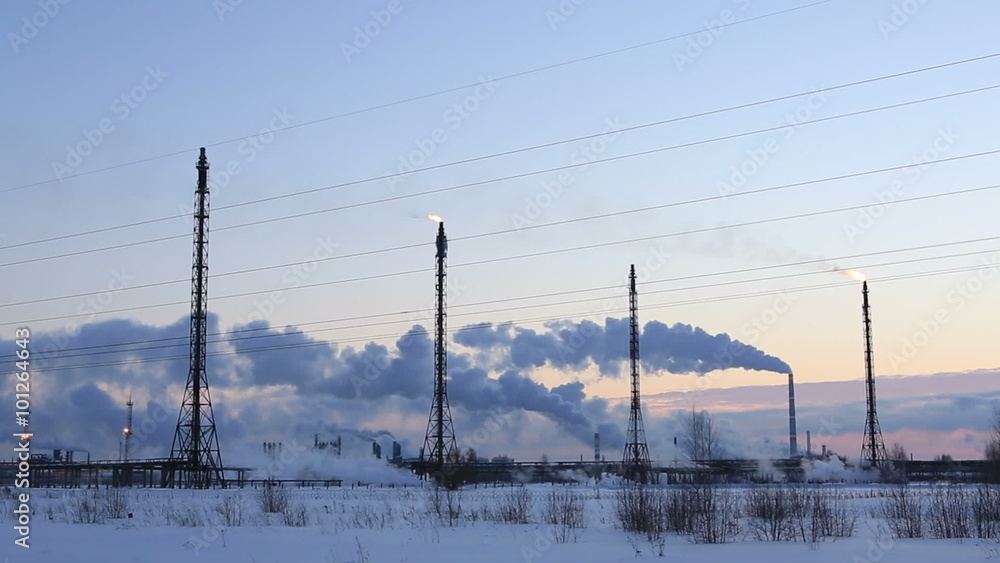 Refinery at sunset sky background. Frosty snowy winter evening. Refinery at sunset sky background. Frosty snowy winter evening.