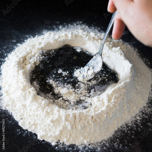 Vászonkép Mixing eggs with squid ink to make black pasta