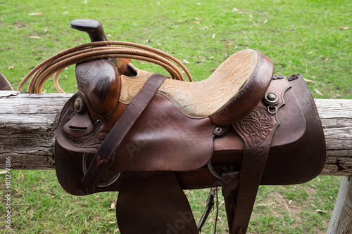 brown horse saddle on wood bar at farm