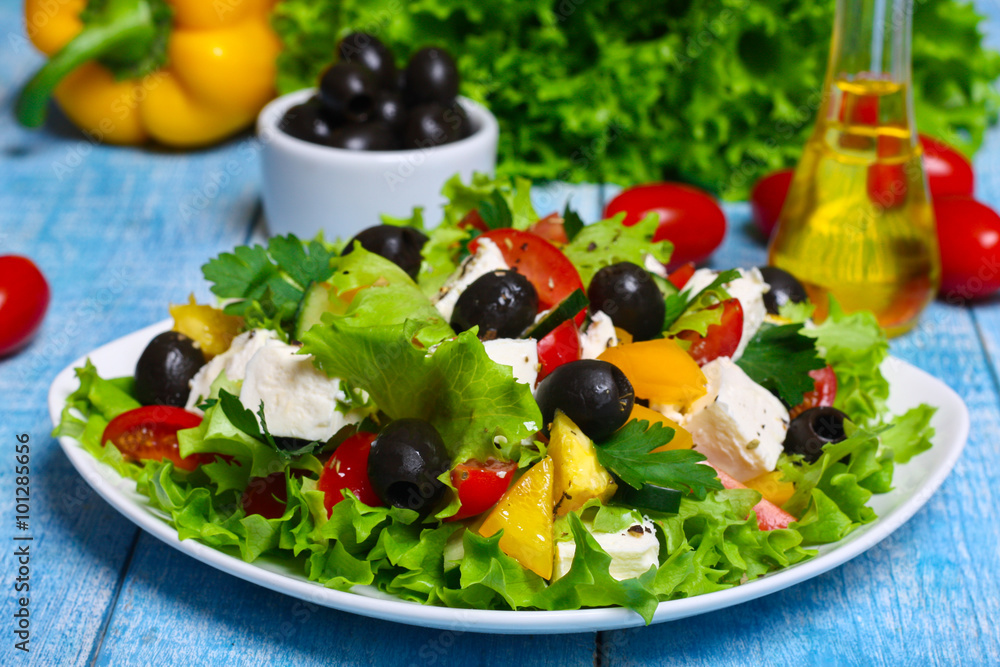 Greek salad with fresh vegetables, feta cheese and black olives on a wooden background Greek salad with fresh vegetables, feta cheese and black olives on a wooden background