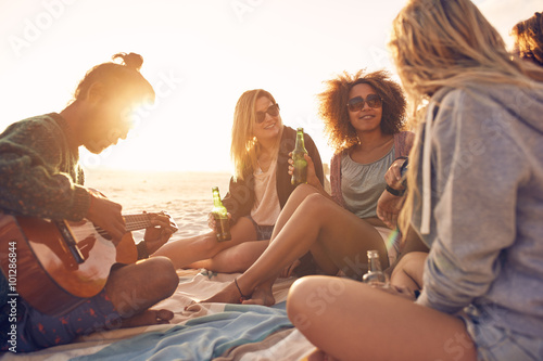 Group of friends partying on the beach at sunset
