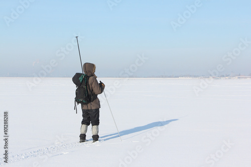 The man the traveler with a backpack skiing on snow of the frozen river 
