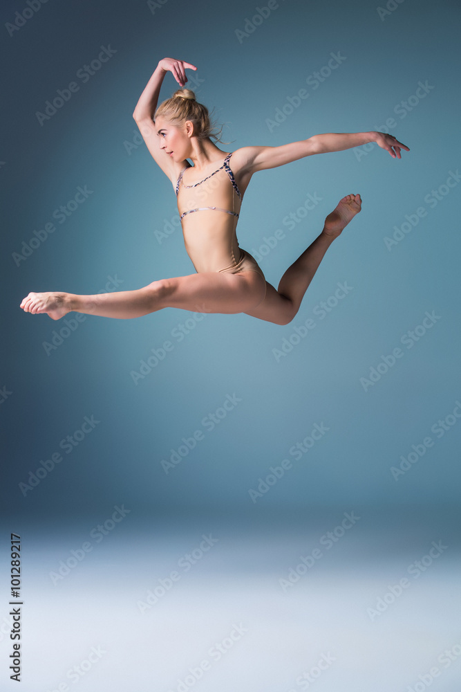Fototapeta premium Young beautiful modern style dancer jumping on a studio background