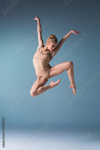 Photographie Young beautiful modern style dancer jumping on a studio background