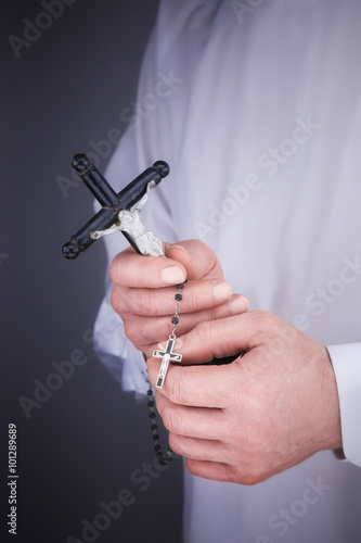 Man's hands with a white cape, crucifix and a black rosary