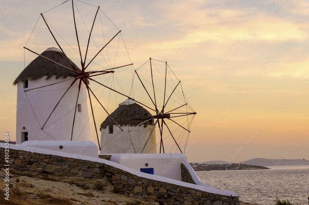     Windmills in Chora,Mykonos,Greece at sunset.Greek whitewashed architecture,a popular landmark,tourist destination on the island of winds,deep blue sky,Aegean sea. Wind mills are now decorative. 