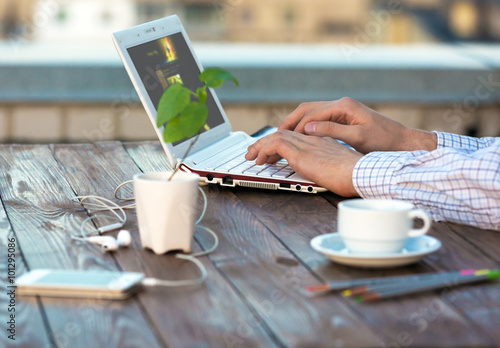 Person typing on Laptop Computer at wooden Desk with Flower photo