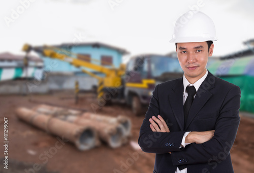 engineer in helmet with arms crossed, construction site backgro