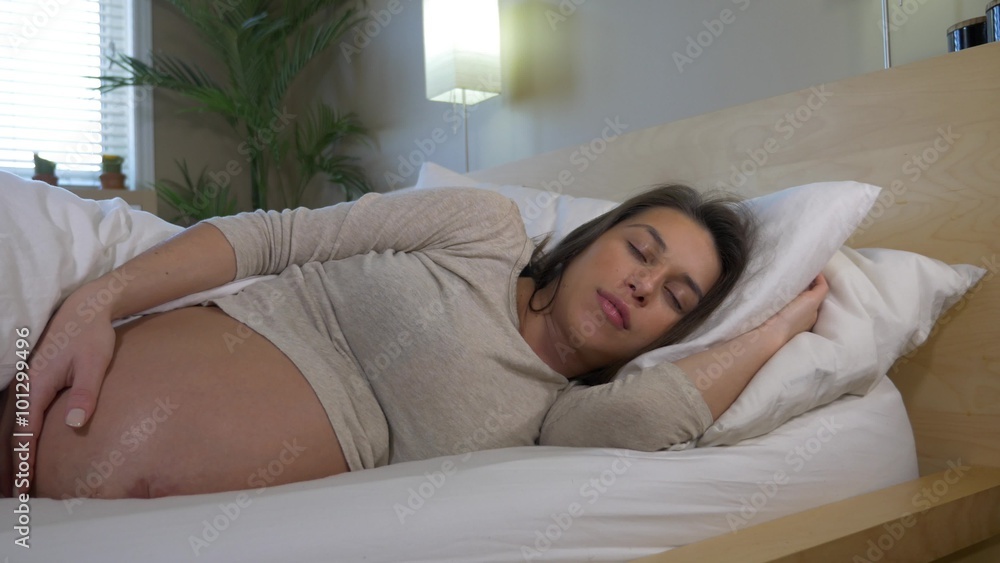 Pregnant woman sleeping in while holding full term belly Pregnant woman sleeping in while holding full term belly