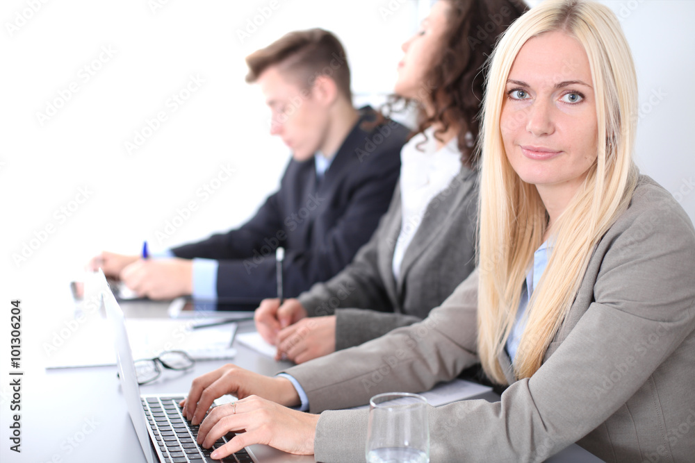A group of business people at a meeting on the background of office. Focus on a beautiful blonde A group of business people at a meeting on the background of office. Focus on a beautiful blonde