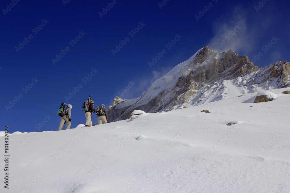 A team of mountaineers going to summit with snow and wind