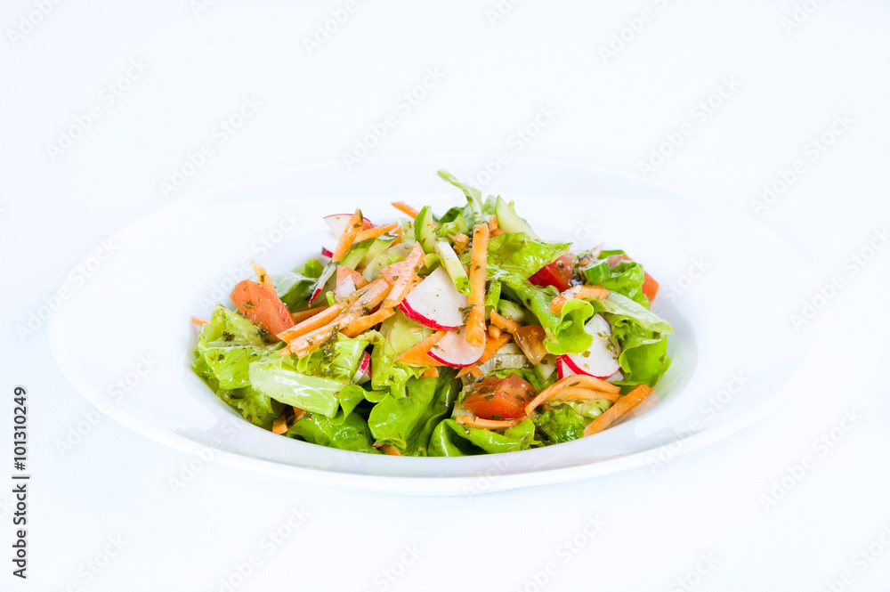 Vegetable salad with radishes, carrots, onions and tomatoes on a white background