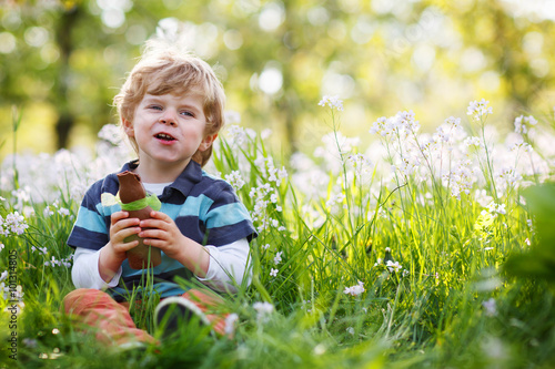 Cute happy little boy eating chocolate bunny  at Easter holiday © Irina Schmidt