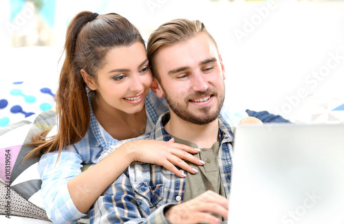 Happy young couple using la...