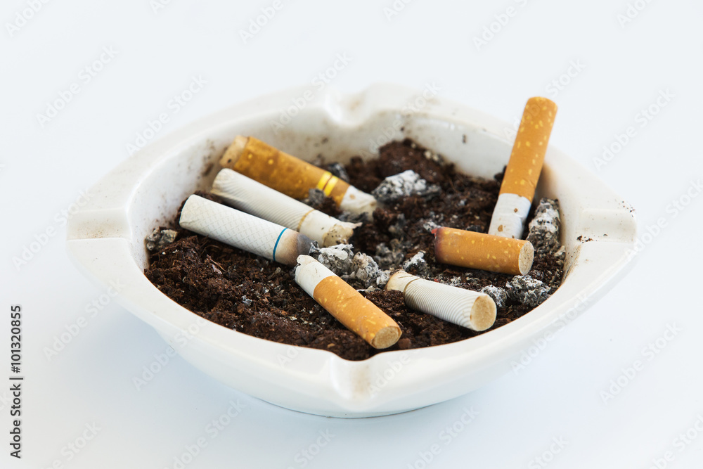 Overhead of burning cigarette in ashtray on white background Overhead of burning cigarette in ashtray on white background