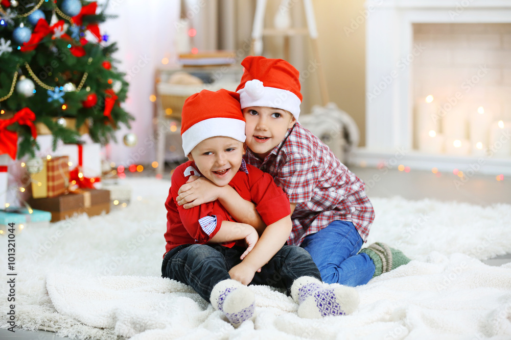 Two cute small brothers hugging on Christmas tree background Two cute small brothers hugging on Christmas tree background