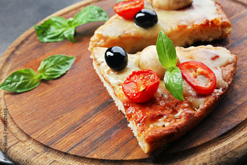 Slices of tasty pizza on round wooden board, close up