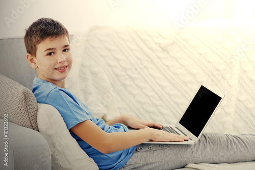 Boy with laptop sitting on ...