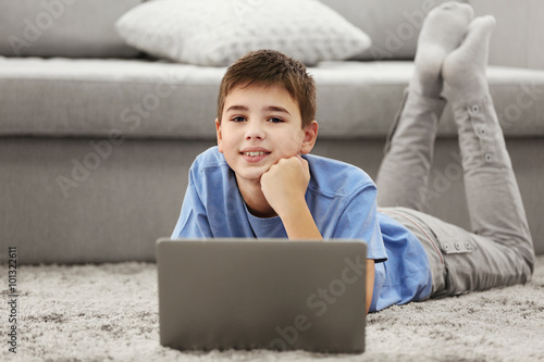 Boy using laptop on a carpe...