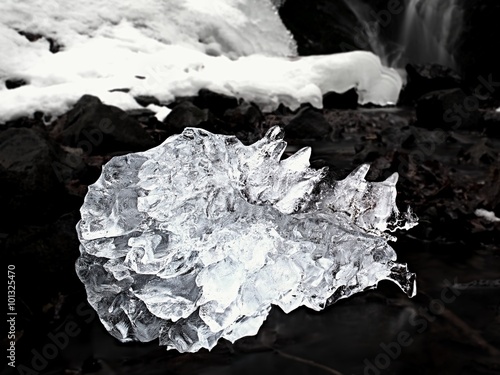 Spiky piece of icrystal ce with abstract cracks inside. Fallen icicle bellow waterfall, photo