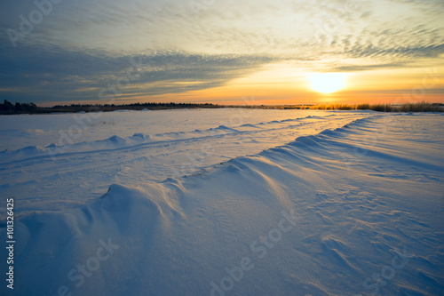 Bright sun sunset winter with road and footprints in the snow.