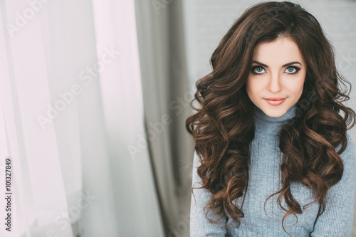 Portrait young beautiful brunette with long curly hair at home. Fototapeta