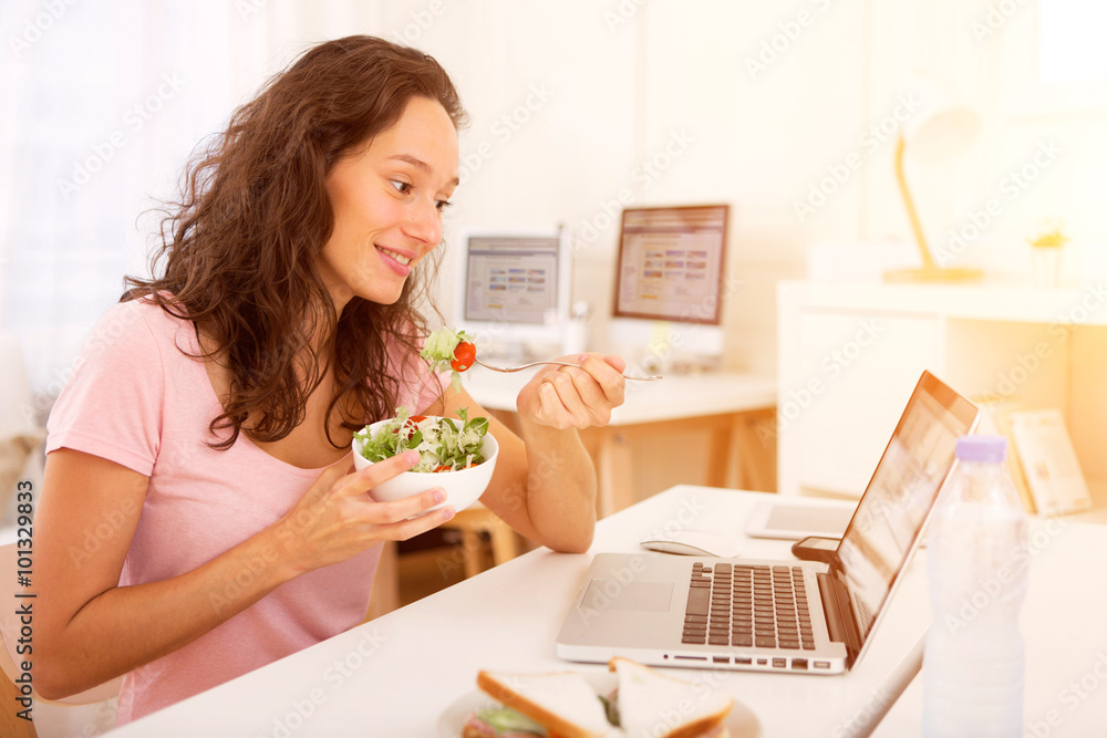 Young attractive student eating while working