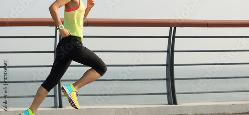 Tableau sur toile young fitness woman runner running on seaside bridge