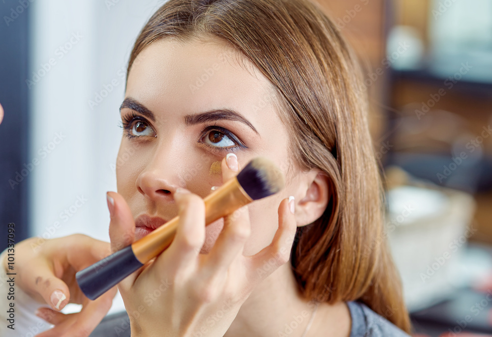 Fotografie young, beautiful girl put on make-up in a beauty salon