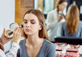 young, beautiful girl put on make-up in a beauty salon