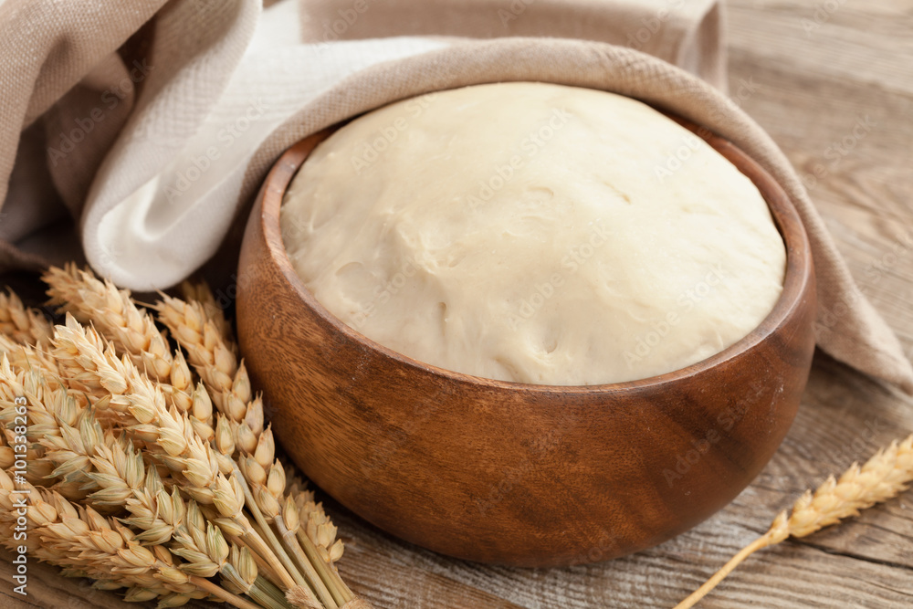 Φωτογραφία dough in a wooden bowl and ears of ripe wheat on the old boards