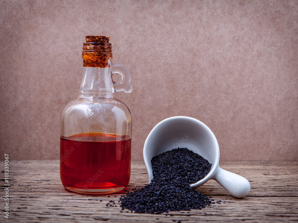 Black sesame oil and sesame seeds in white bowl set up on grunge