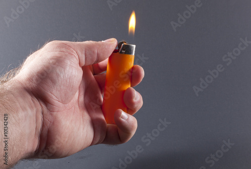 Hand holding a lit orange lighter