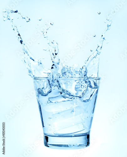 Splashing of water with ice in glass on white background.