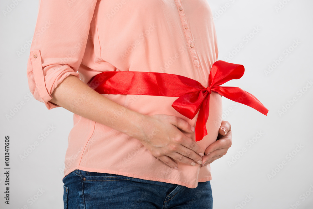 Φωτογραφία Pregnant Woman With Red Ribbon Tied To Belly
