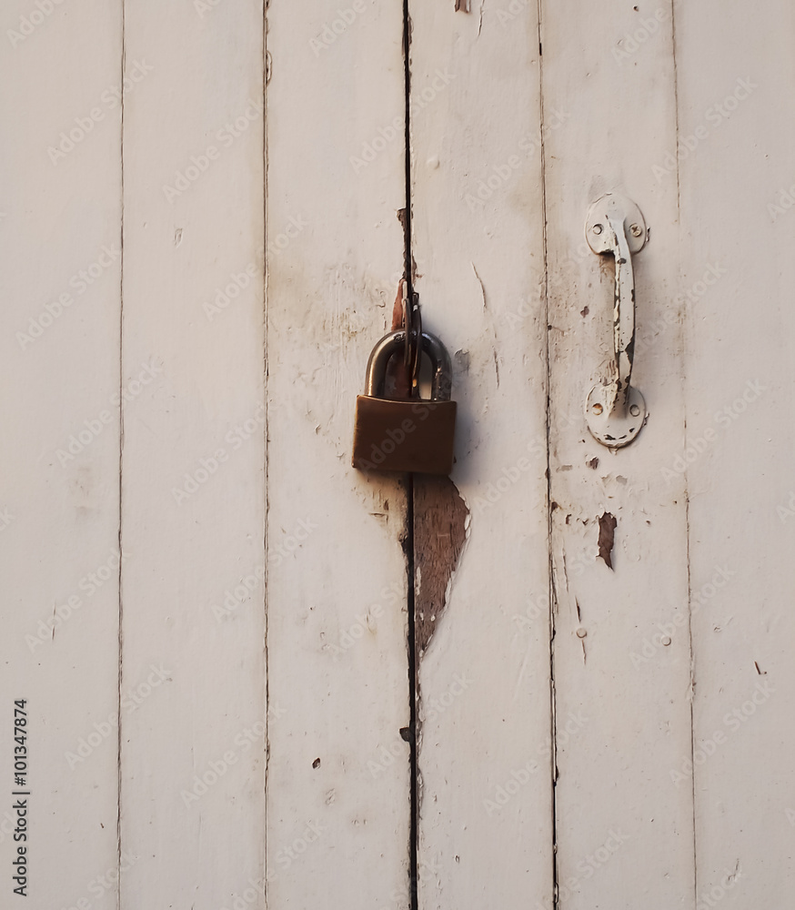 Old rusty padlock on white weathered wooden door
Old rusty padlock on white weathered wooden door